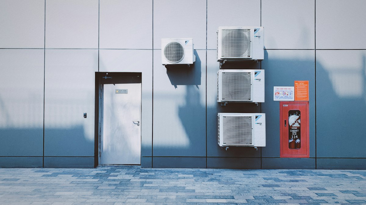 Several air conditioner outdoor units mounted on a grey wall