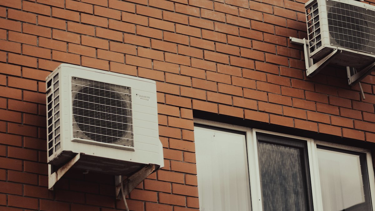 Air conditioner units mounted on a brick building beside windows
